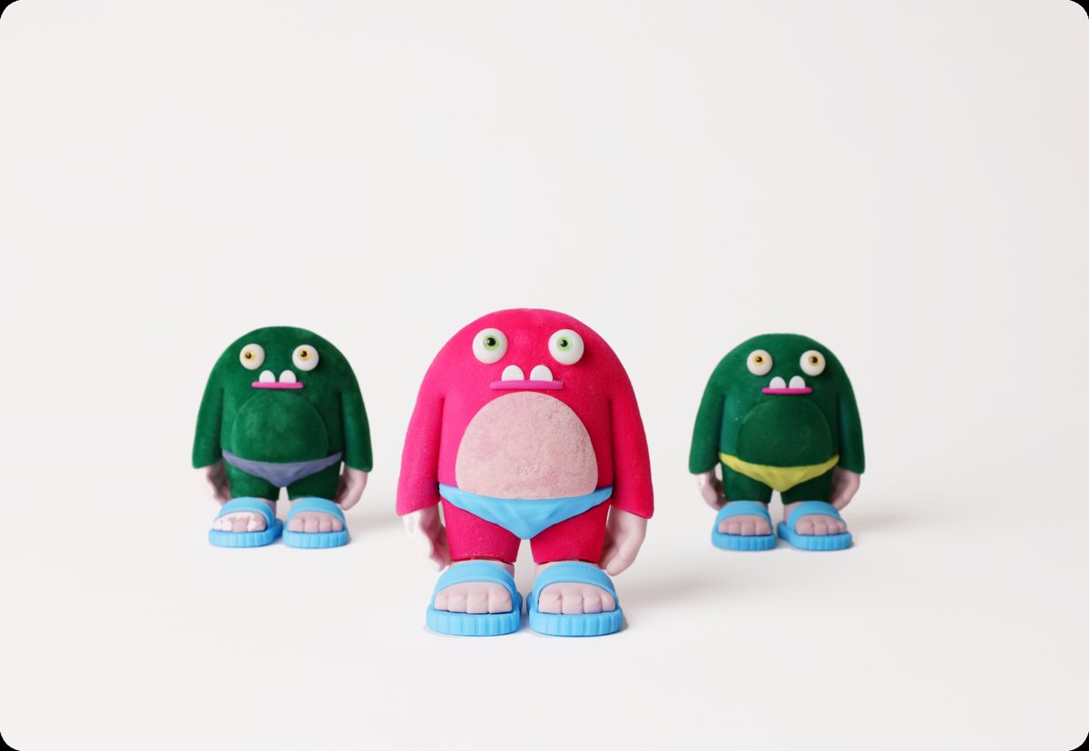 Three flocked collectible monster figurines in sandals