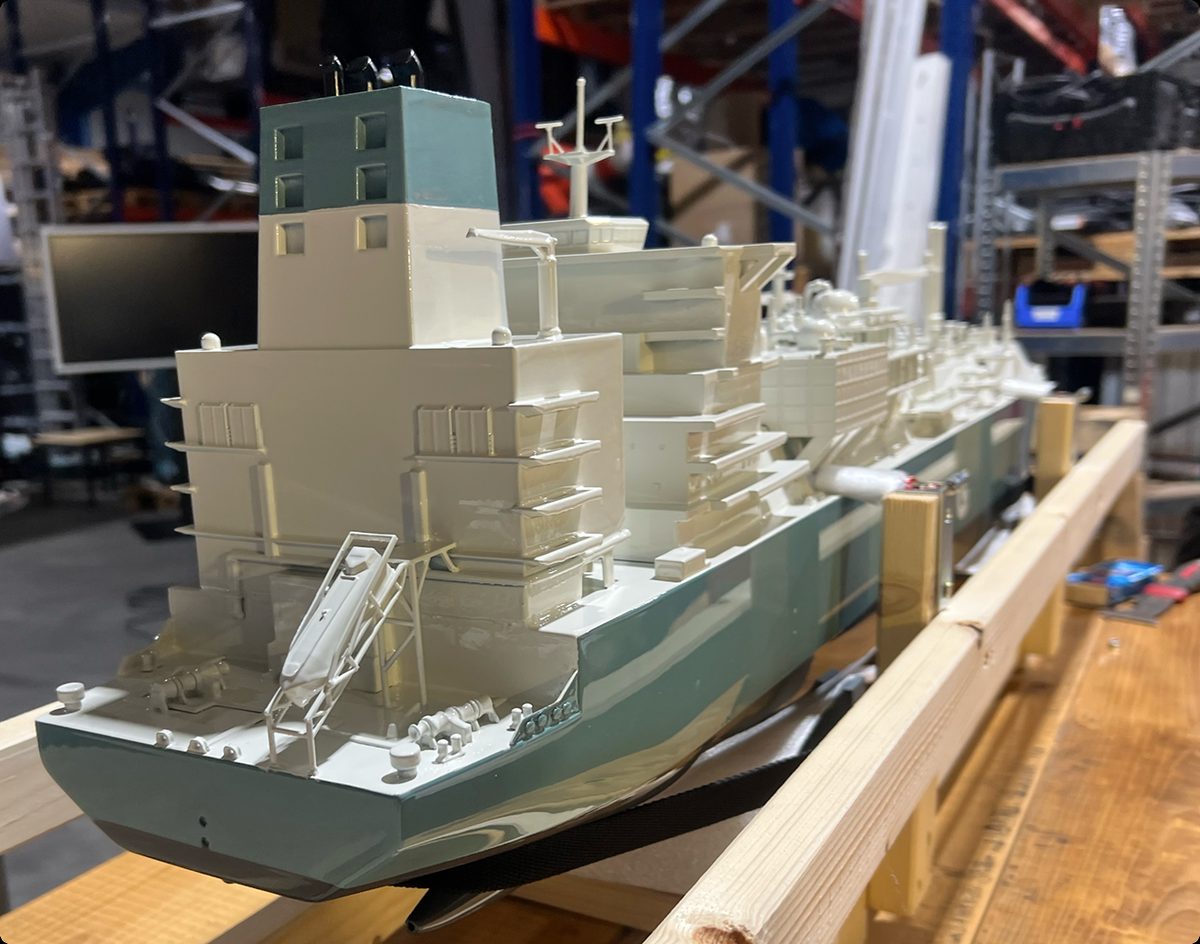 Large 3D-printed tanker ship model on a wooden cradle in the workshop